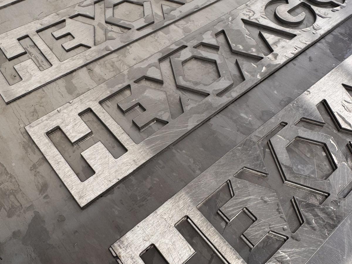 Hexagonal metal letters precision-cut by waterjet for custom signage